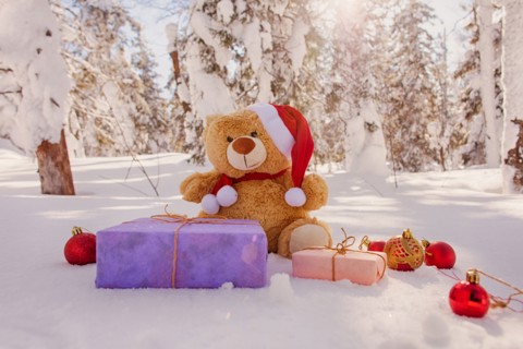 Teddy bear with Christmas gifts and ornaments in snow
