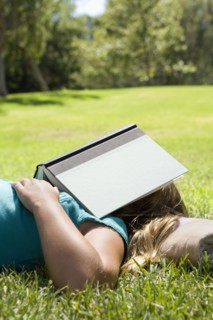 Girl sleeping in grass with book on her head