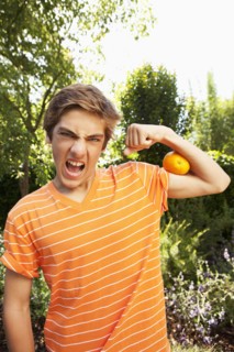 Caucasian teenager squeezing orange with arm