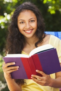 Mixed race woman reading book outdoors