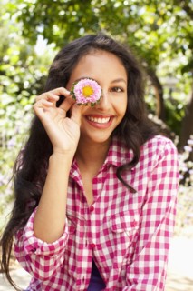 Mixed race teenager holding flower in front of her face