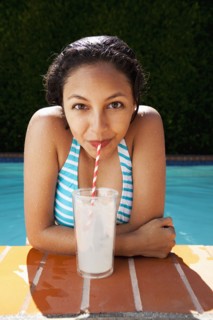 Mixed race girl drinking lemonade near swimming pool