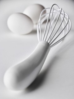 Close up of white whisk and eggs