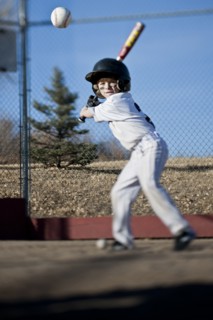 Caucasian boy hitting baseball on field