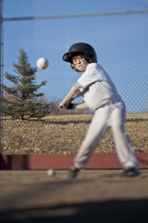Caucasian boy hitting baseball on field