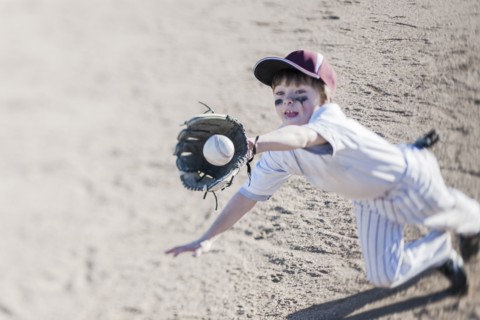 Caucasian boy catching baseball on field