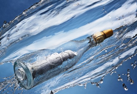 Close up of message in a bottle splashing in water