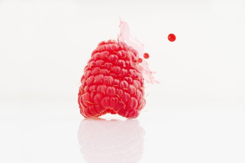 Close up of juice splashing on raspberry