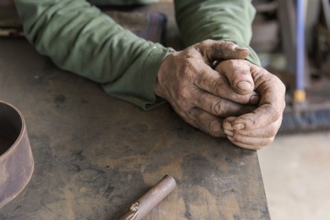Rugged hands of artist leaning on table in workshop
