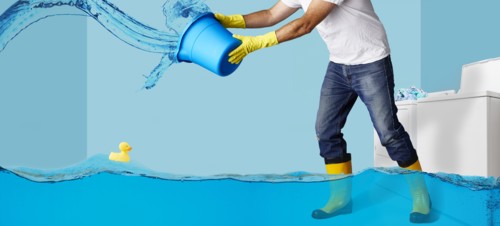 Man throwing water from bucket in flooding laundry room