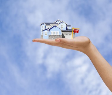 Hand of woman holding home for sale in sky