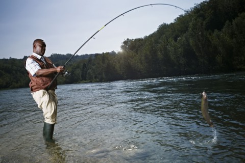 Black man catching fish in stream