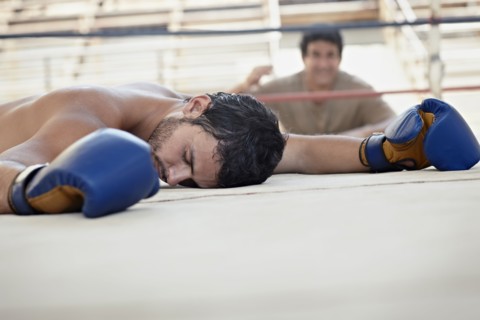 Knocked-out Hispanic boxer laying on ground