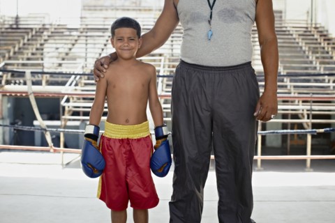 Hispanic trainer standing with boy in boxing gear