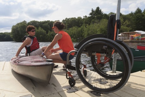 Caucasian instructor helping paraplegic woman with kayak