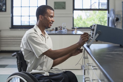 African American paraplegic student performing experiment in science classroom