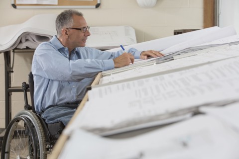 Caucasian architect in wheelchair working in office