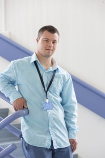 Caucasian man with Down Syndrome wearing badge on stairs