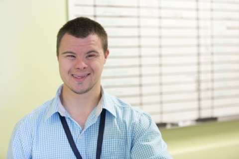 Caucasian man with Down Syndrome smiling in office