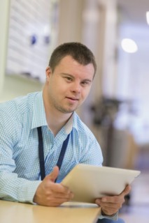Caucasian man with Down Syndrome using digital tablet in hospital