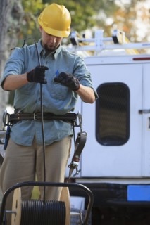 Caucasian worker unrolling cable spool