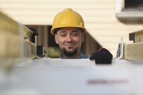 Caucasian installer pulling ladder from truck roof