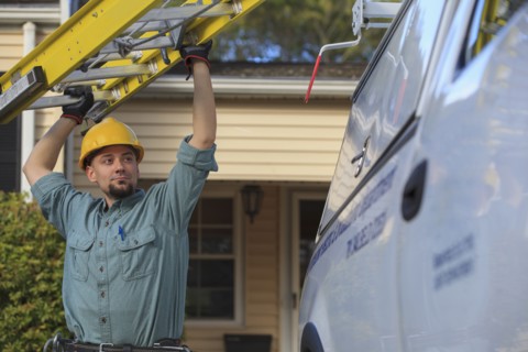 Caucasian worker pulling ladder from truck roof