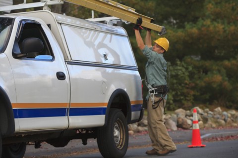 Caucasian worker loading ladder on truck