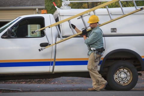 Caucasian worker carrying ladder near truck