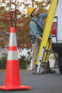 Caucasian worker loading ladder on truck