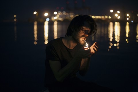 Caucasian man lighting cigarette at waterfront