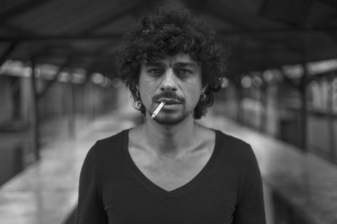 Serious Mixed Race man smoking cigarettes