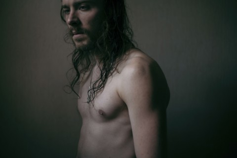 Pensive Caucasian man with long hair and bare chest