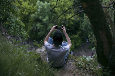 Caucasian man photographing with cell phone in woods