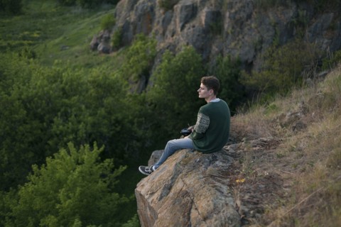 Caucasian man sitting on a rock admiring landscape