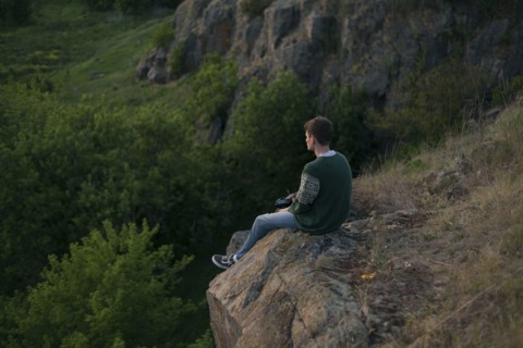 Caucasian man sitting on a rock admiring landscape