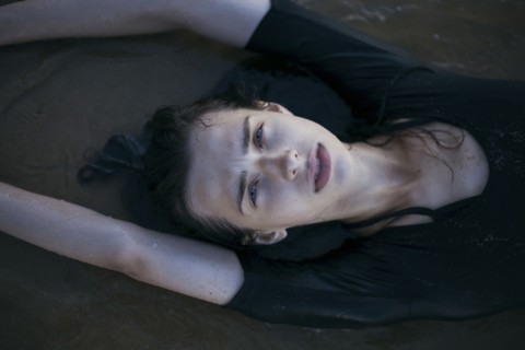 Caucasian woman laying on beach in waves