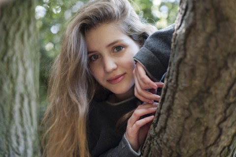 Portrait of smiling Caucasian teenage girl leaning on tree