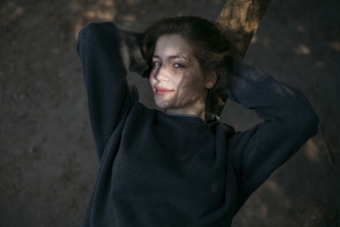 Portrait of smiling Caucasian teenage girl leaning on tree