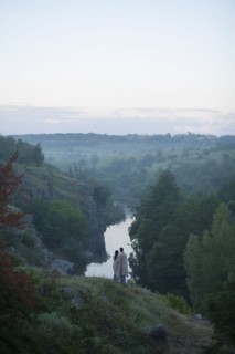 Caucasian couple standing on hill admiring river