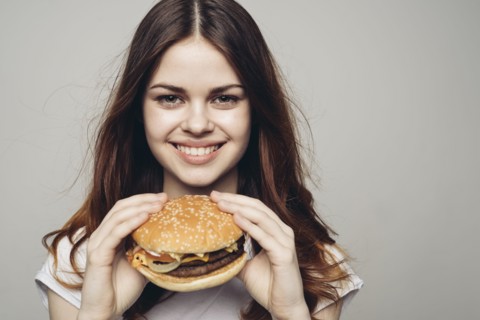 Smiling Caucasian woman holding cheeseburger