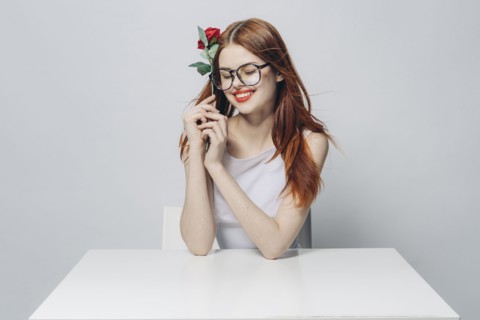 Caucasian woman sitting at windy table holding rose
