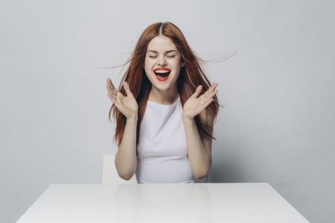 Excited Caucasian woman sitting at windy table