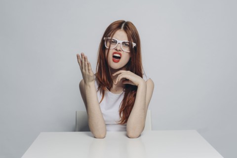 Caucasian woman with attitude sitting at table wearing white eyeglasses