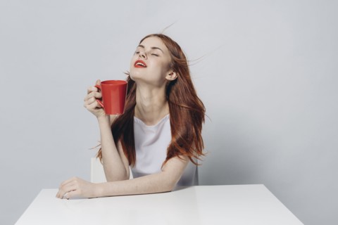 Caucasian woman sitting at windy table holding red cup