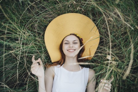 Caucasian woman wearing hat laying in grass
