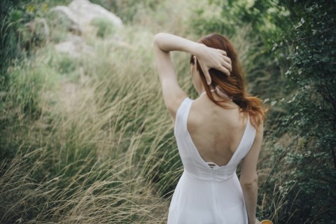 Caucasian woman standing in tall grass with hand in hair