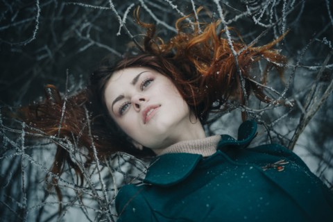 Serious Caucasian woman laying on icy branches
