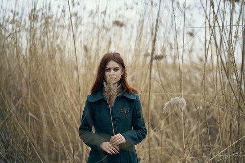 Caucasian woman standing in field holding stalk of grass