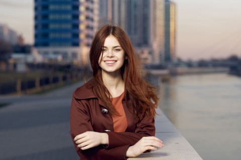 Smiling Caucasian woman leaning on wall at waterfront